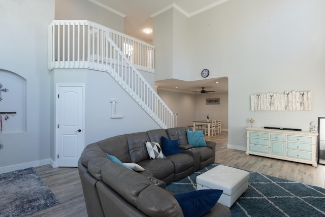 living area featuring wood finished floors, stairway, a high ceiling, crown molding, and baseboards