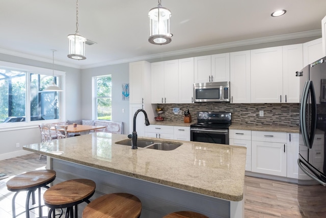 kitchen with a sink, backsplash, appliances with stainless steel finishes, and crown molding
