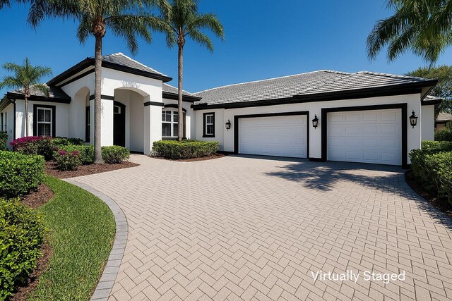 2488 SW Longwood Dr, Palm City, FL 34990 - view of front of house featuring an attached garage, decorative driveway, stucco siding, and a tile roof