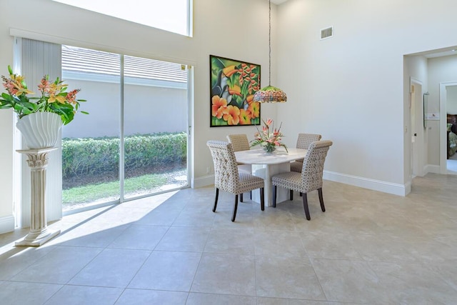 dining room featuring a high ceiling, light tile patterned floors, baseboards, and a wealth of natural light