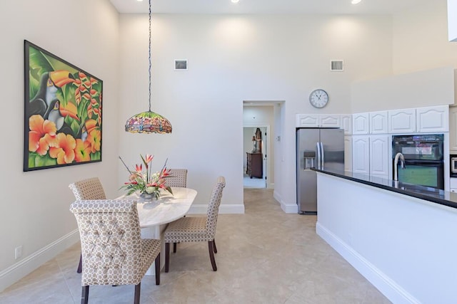 dining room featuring visible vents, baseboards, and a towering ceiling