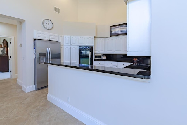 kitchen featuring dark countertops, white cabinets, a peninsula, and stainless steel refrigerator with ice dispenser