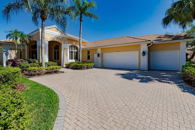 2488 SW Longwood Dr, Palm City, FL 34990 - view of front of home featuring a garage, stucco siding, a tile roof, and decorative driveway