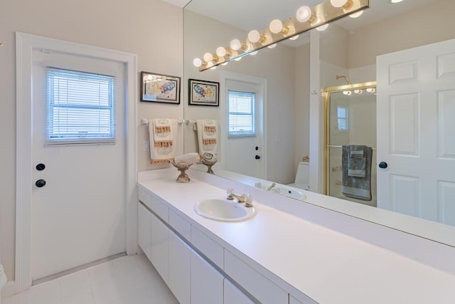 bathroom featuring toilet, vanity, and a shower with shower door