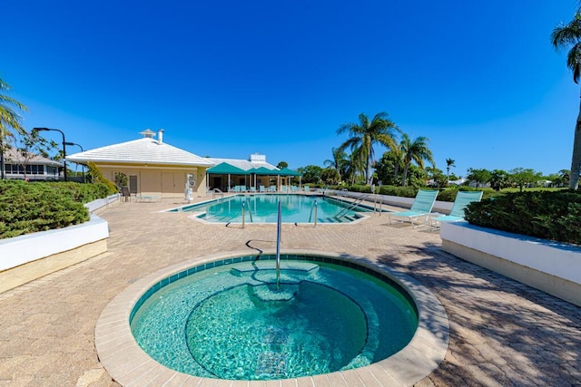 community pool with a hot tub and a patio