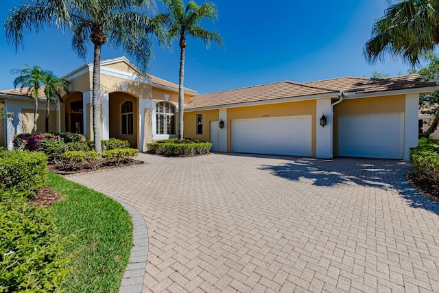 single story home featuring stucco siding, an attached garage, and decorative driveway