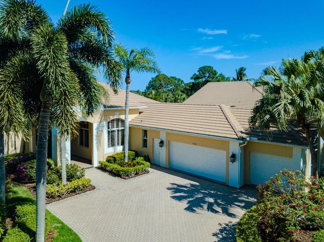 view of front of property featuring stucco siding, decorative driveway, and a garage