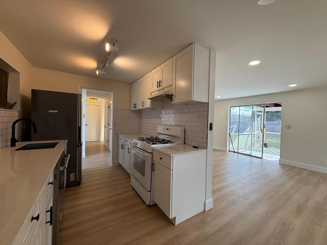 kitchen featuring under cabinet range hood, light wood-style flooring, white gas stove, and a sink