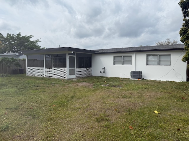 back of property with central AC, a yard, a sunroom, and stucco siding