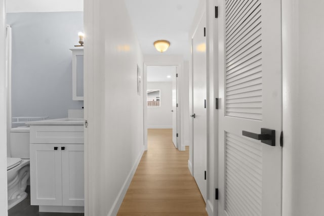 corridor featuring light wood-style flooring and baseboards