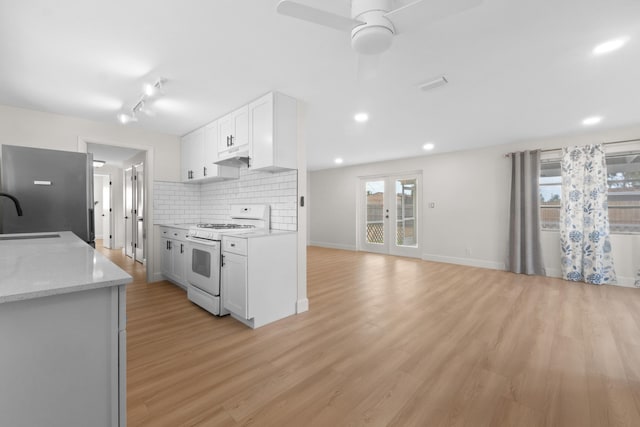 kitchen featuring white range with gas cooktop, white cabinets, decorative backsplash, light wood-type flooring, and recessed lighting