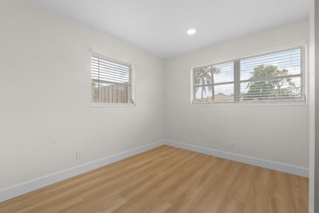 unfurnished room with baseboards, plenty of natural light, wood finished floors, and recessed lighting