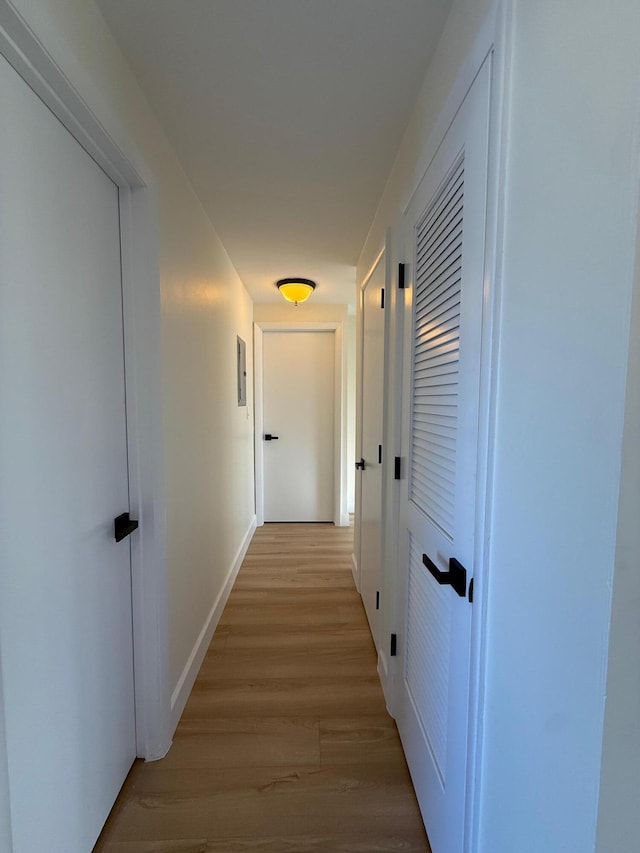 hall with light wood-style flooring and baseboards