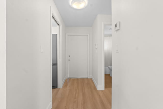hallway featuring light wood-style flooring and baseboards