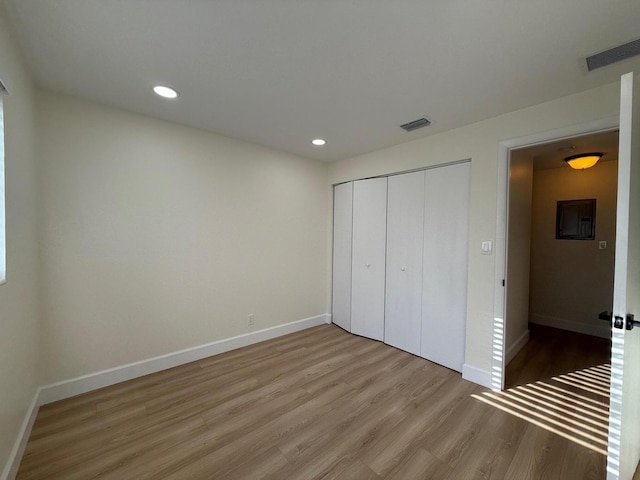 unfurnished bedroom with visible vents, wood finished floors, recessed lighting, a closet, and baseboards