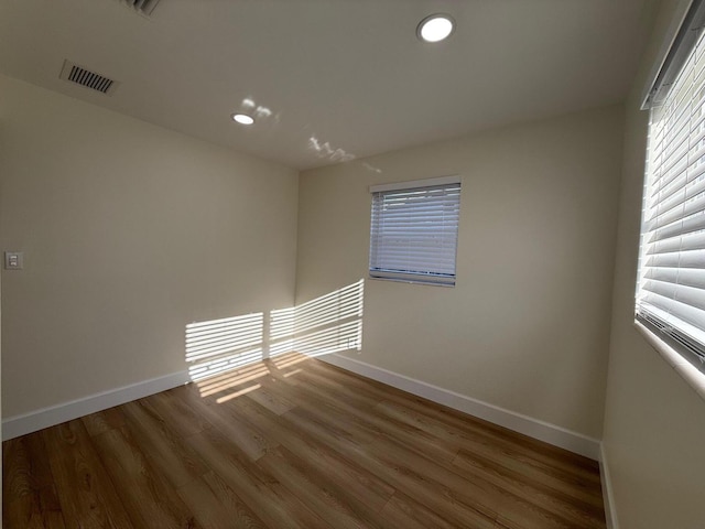 empty room with visible vents, recessed lighting, baseboards, and wood finished floors