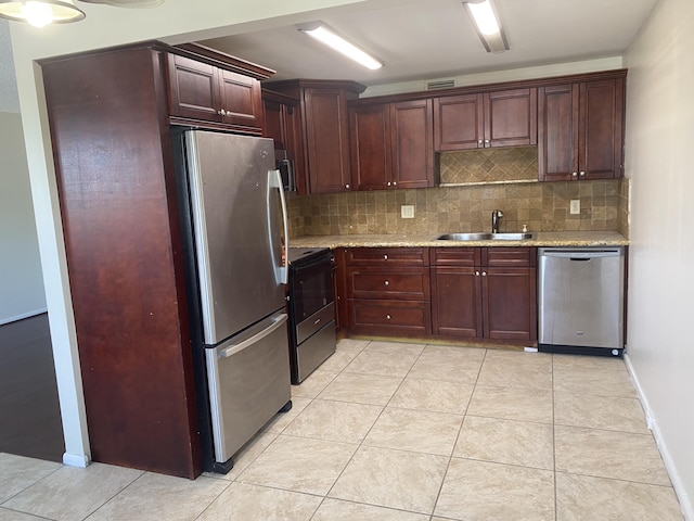 kitchen featuring a sink, tasteful backsplash, stainless steel appliances, light tile patterned floors, and light stone countertops