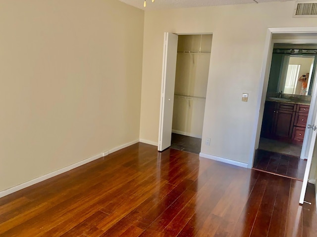 unfurnished bedroom featuring baseboards, dark wood-style floors, visible vents, and a sink