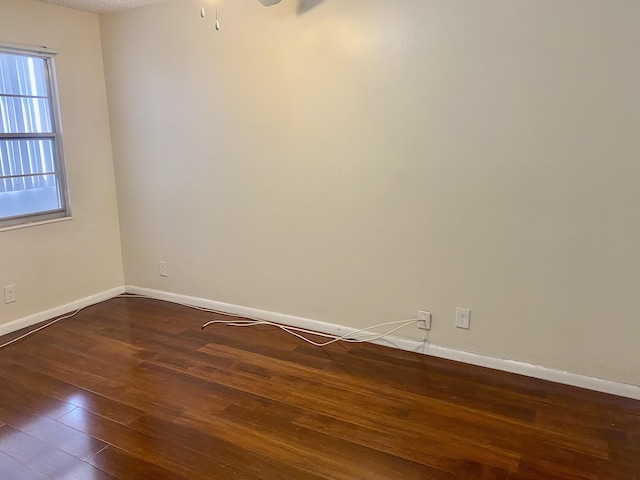 spare room with baseboards and wood finished floors