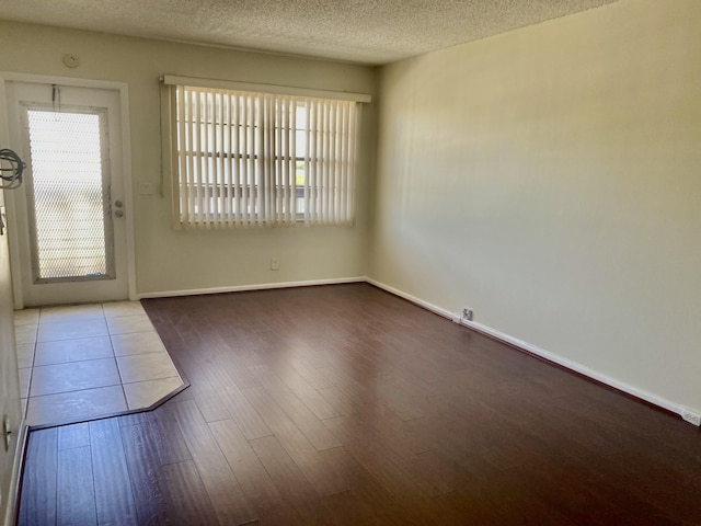 interior space featuring baseboards, a textured ceiling, and wood finished floors