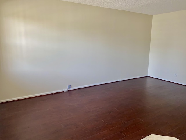 empty room featuring dark wood finished floors, baseboards, and a textured ceiling