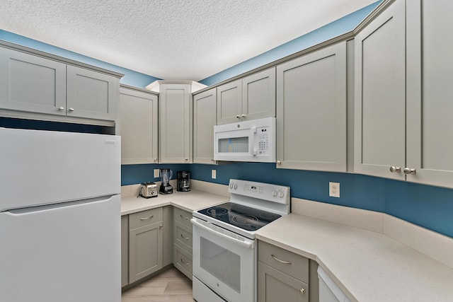 kitchen with white appliances, light countertops, gray cabinets, and a textured ceiling