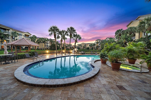 pool at dusk featuring a gazebo, a community pool, and a patio area