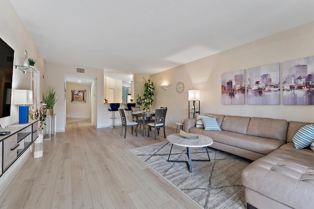 living area featuring visible vents, baseboards, and light wood finished floors