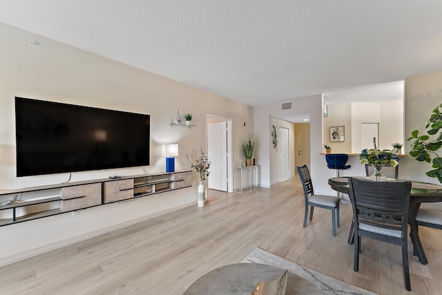 living room featuring visible vents, a textured ceiling, and light wood-type flooring