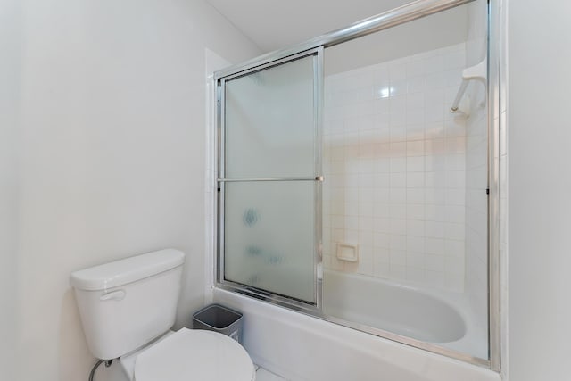 bathroom with toilet and bath / shower combo with glass door