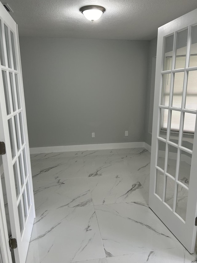 empty room with a textured ceiling and baseboards