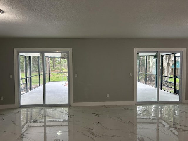 empty room featuring baseboards, marble finish floor, and a textured ceiling