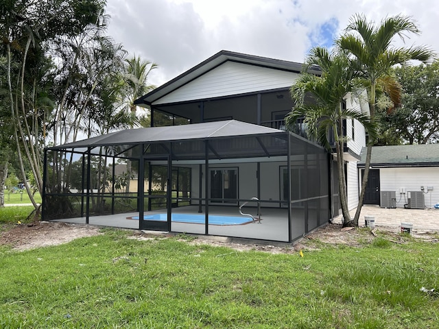 back of house with a lanai, central AC unit, a lawn, a patio area, and an outdoor pool