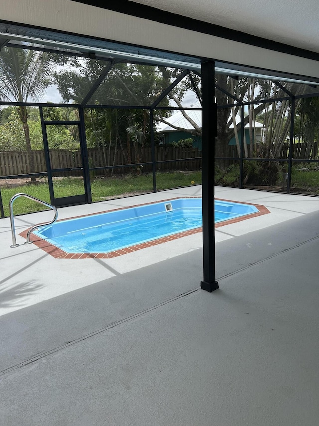 view of pool featuring glass enclosure, a patio area, and fence