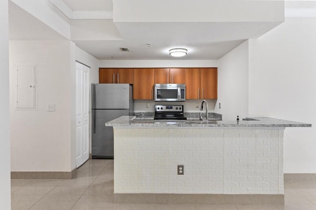 kitchen with light tile patterned floors, electric panel, appliances with stainless steel finishes, brown cabinetry, and a sink