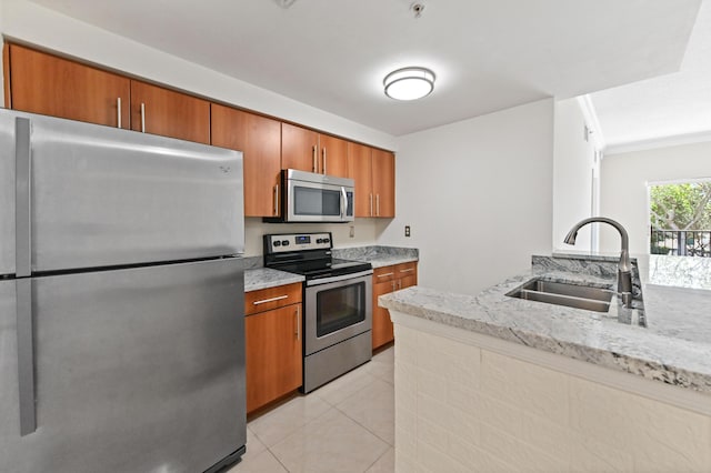 kitchen with light stone countertops, light tile patterned floors, appliances with stainless steel finishes, brown cabinetry, and a sink