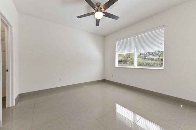 empty room featuring light tile patterned floors, baseboards, and ceiling fan