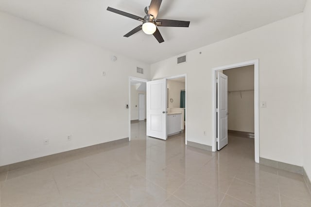 unfurnished bedroom with visible vents, a walk in closet, and baseboards