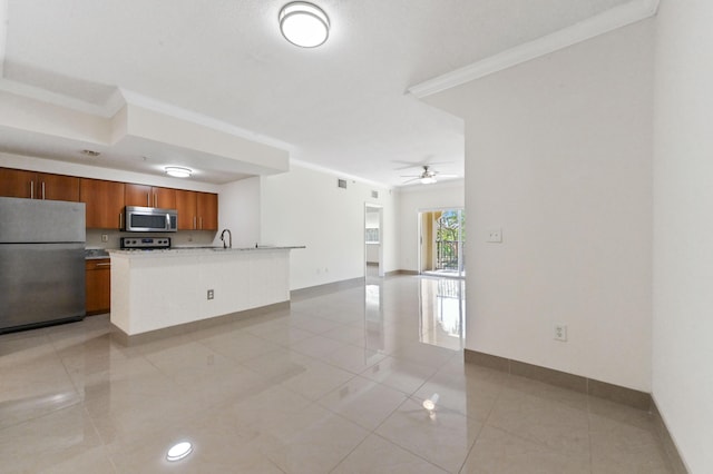 kitchen with brown cabinets, light countertops, appliances with stainless steel finishes, crown molding, and open floor plan