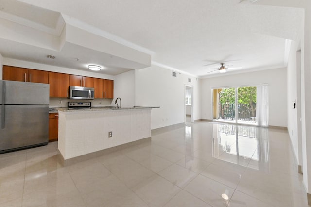 kitchen with visible vents, brown cabinets, a sink, open floor plan, and appliances with stainless steel finishes