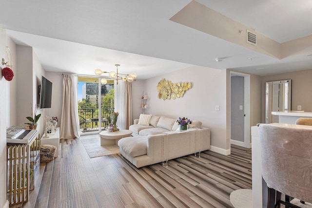 living room featuring an inviting chandelier, wood finished floors, visible vents, and baseboards