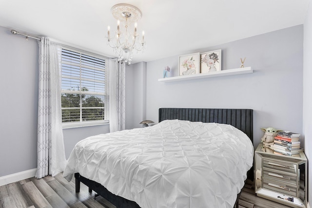 bedroom with baseboards, a notable chandelier, and wood finished floors