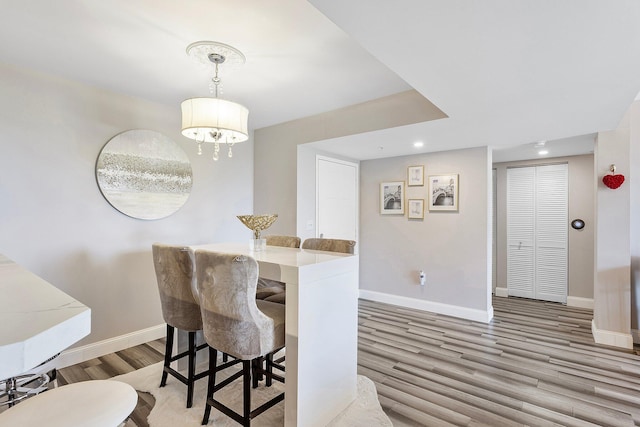 dining space with a chandelier, recessed lighting, baseboards, and wood finished floors