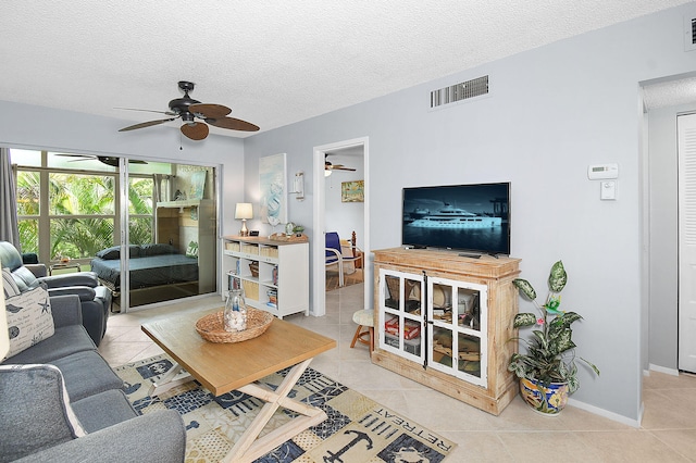 living area featuring light tile patterned floors, baseboards, visible vents, and a textured ceiling