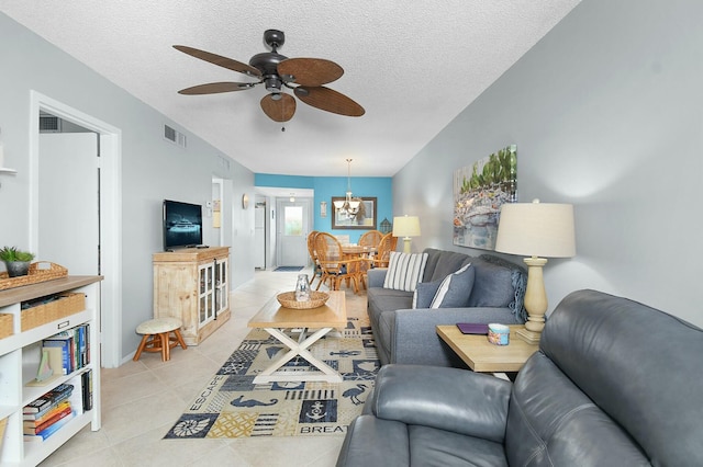 living area featuring light tile patterned floors, visible vents, a textured ceiling, and ceiling fan with notable chandelier