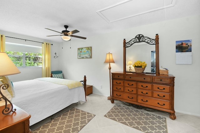 bedroom with baseboards, attic access, light tile patterned flooring, a textured ceiling, and a ceiling fan