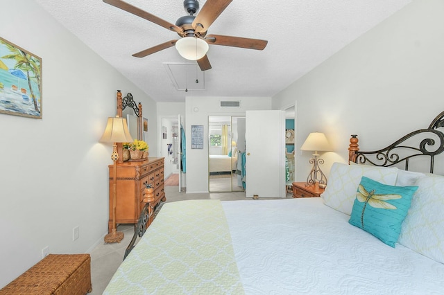 tiled bedroom featuring ensuite bath, visible vents, a textured ceiling, and attic access