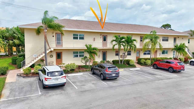 view of property with stairway and uncovered parking