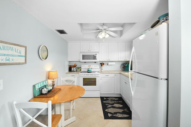 kitchen featuring white appliances, visible vents, a tray ceiling, light tile patterned flooring, and white cabinets