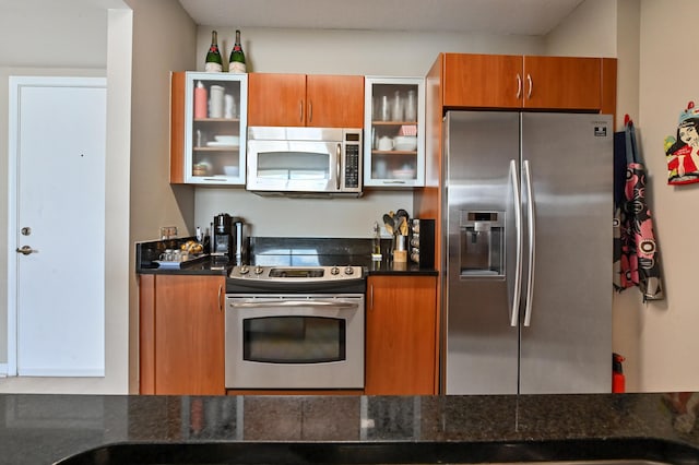 kitchen with brown cabinetry, stainless steel appliances, and glass insert cabinets